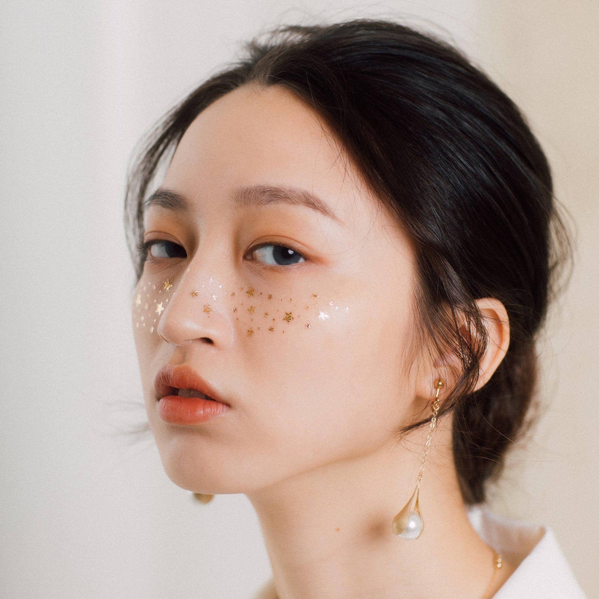 alternative look girl wearing metallic gold freckle transfer tattoos on face