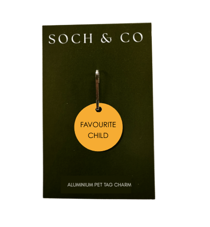 Yellow circular dog collar charm with 'Favourite Child' text on a black card with 'SOCH & CO' branding.