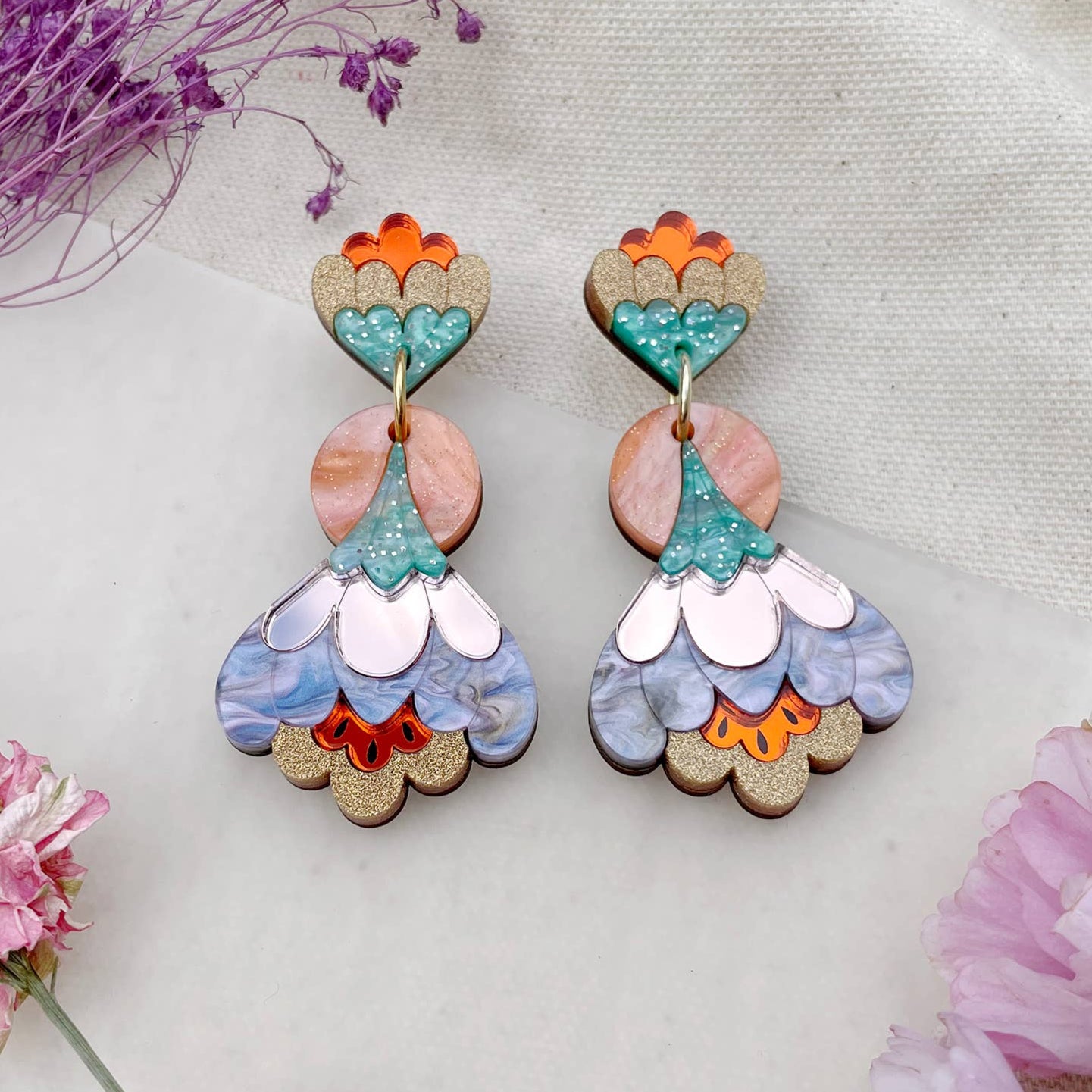 Colorful floral earrings on a light background with flowers around