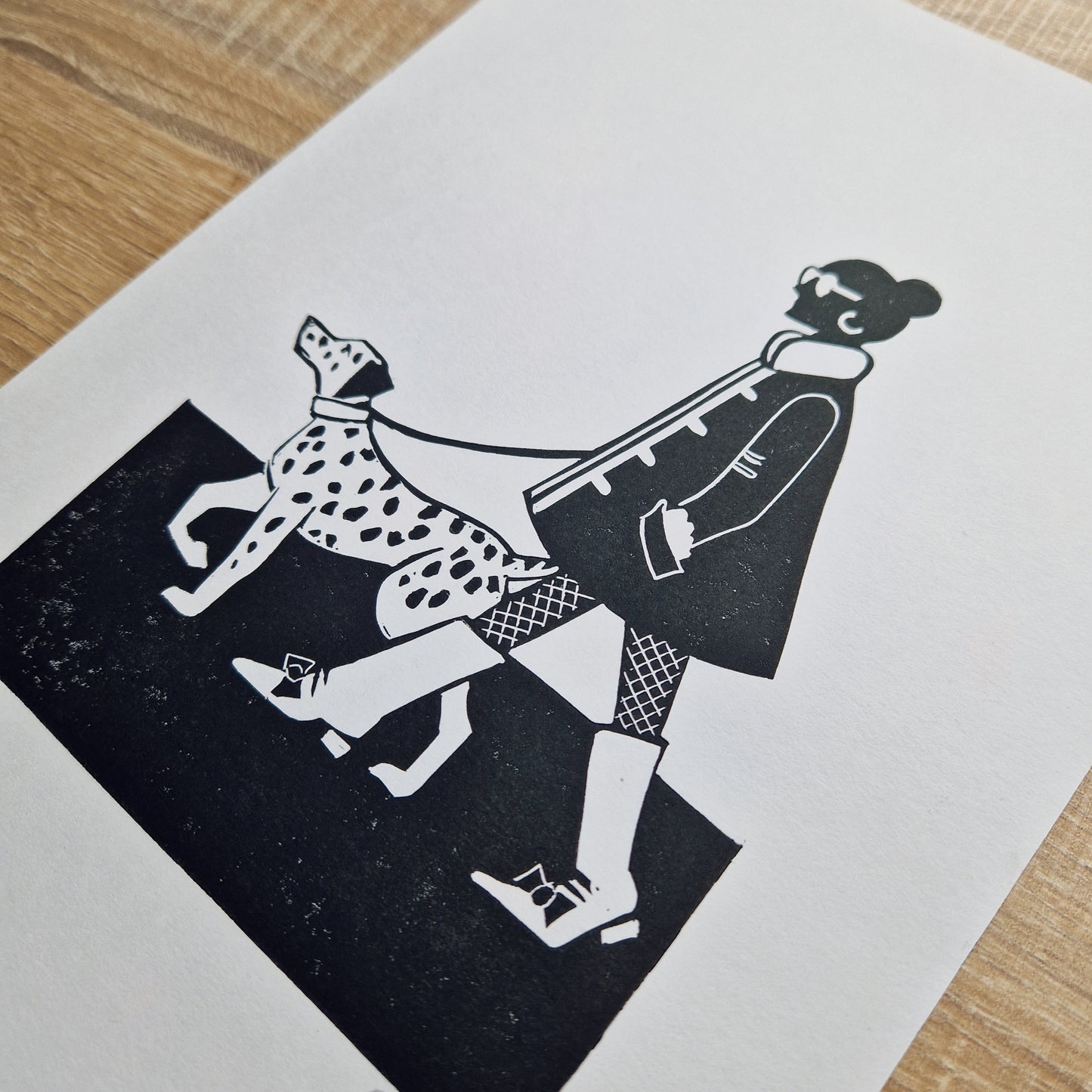 A black and white linocut print of a woman walking a dalmatian on a leash.