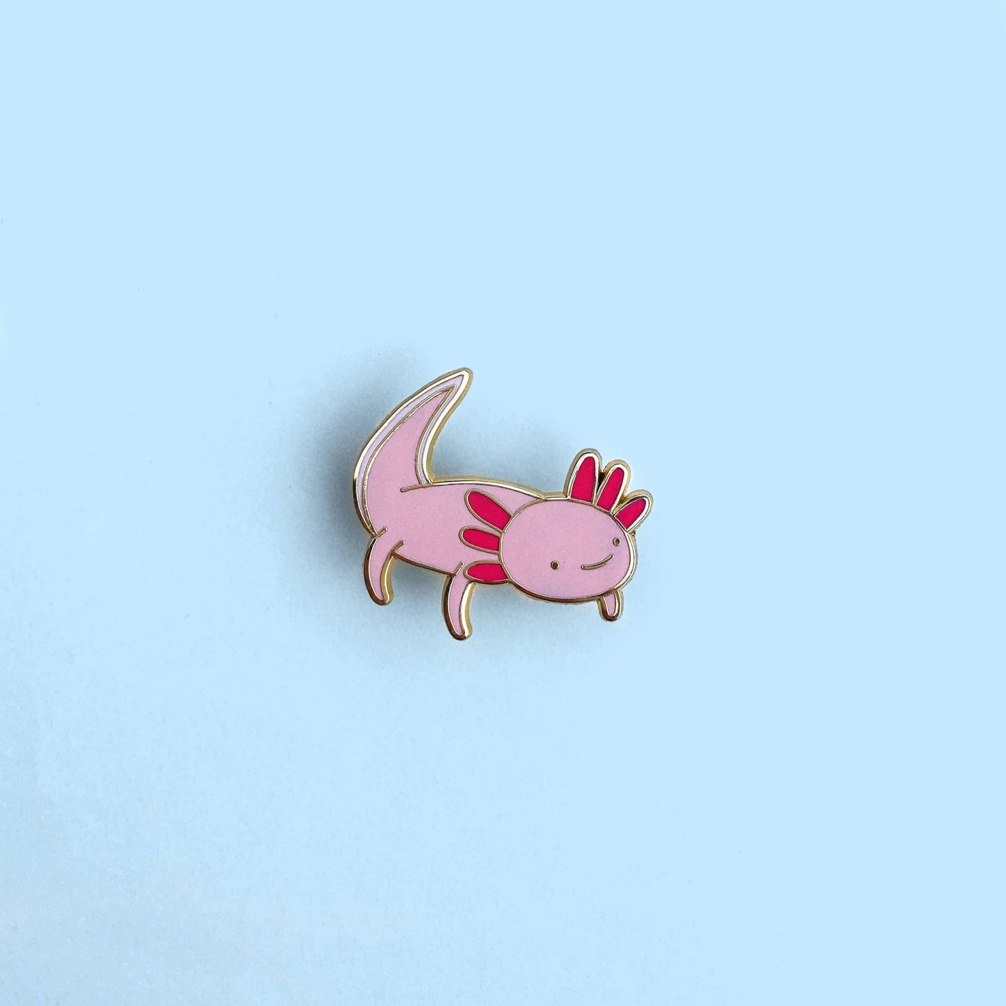 Pink axolotl enamel pin on a light blue background