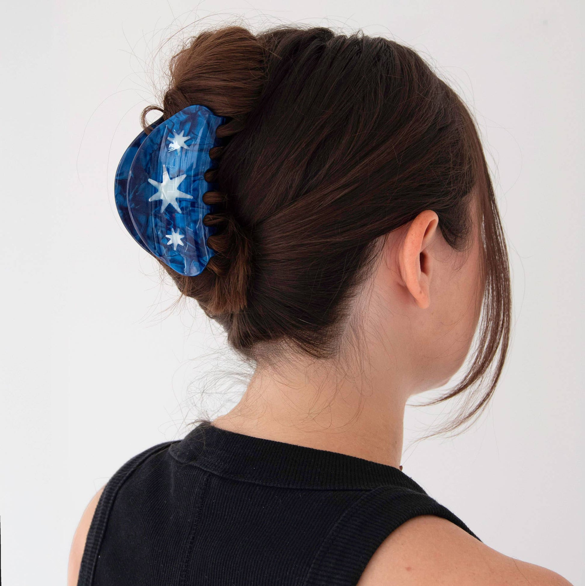 Blue hair clip with star design in a bun on a white background