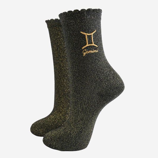 A pair of black socks with gold sparkle and the embroidered gold Gemini star sign.
