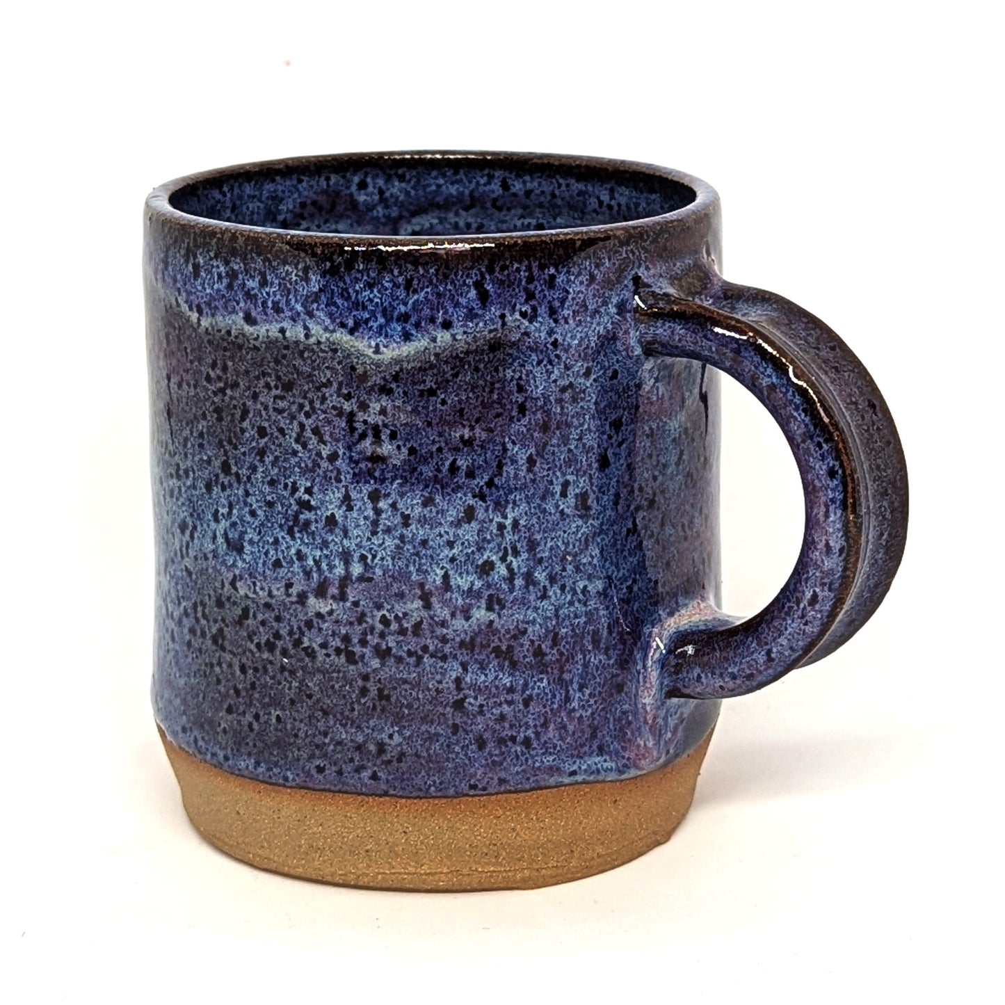A handcrafted ceramic mug with a purple and blue sunset color palette and a matte finish on the lower half, transitioning to a glossy finish on the upper half.