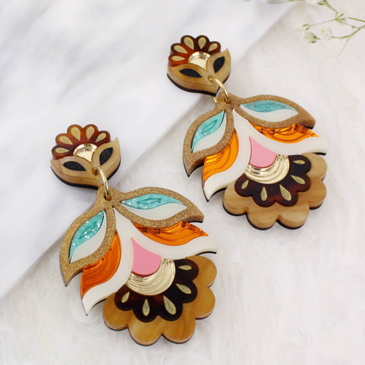 Colorful floral earrings on a white fabric background with small flowers.