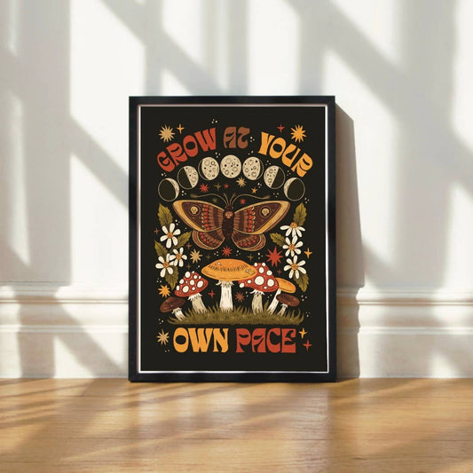 Framed artwork with a butterfly and mushroom design on a black background, featuring motivational text.