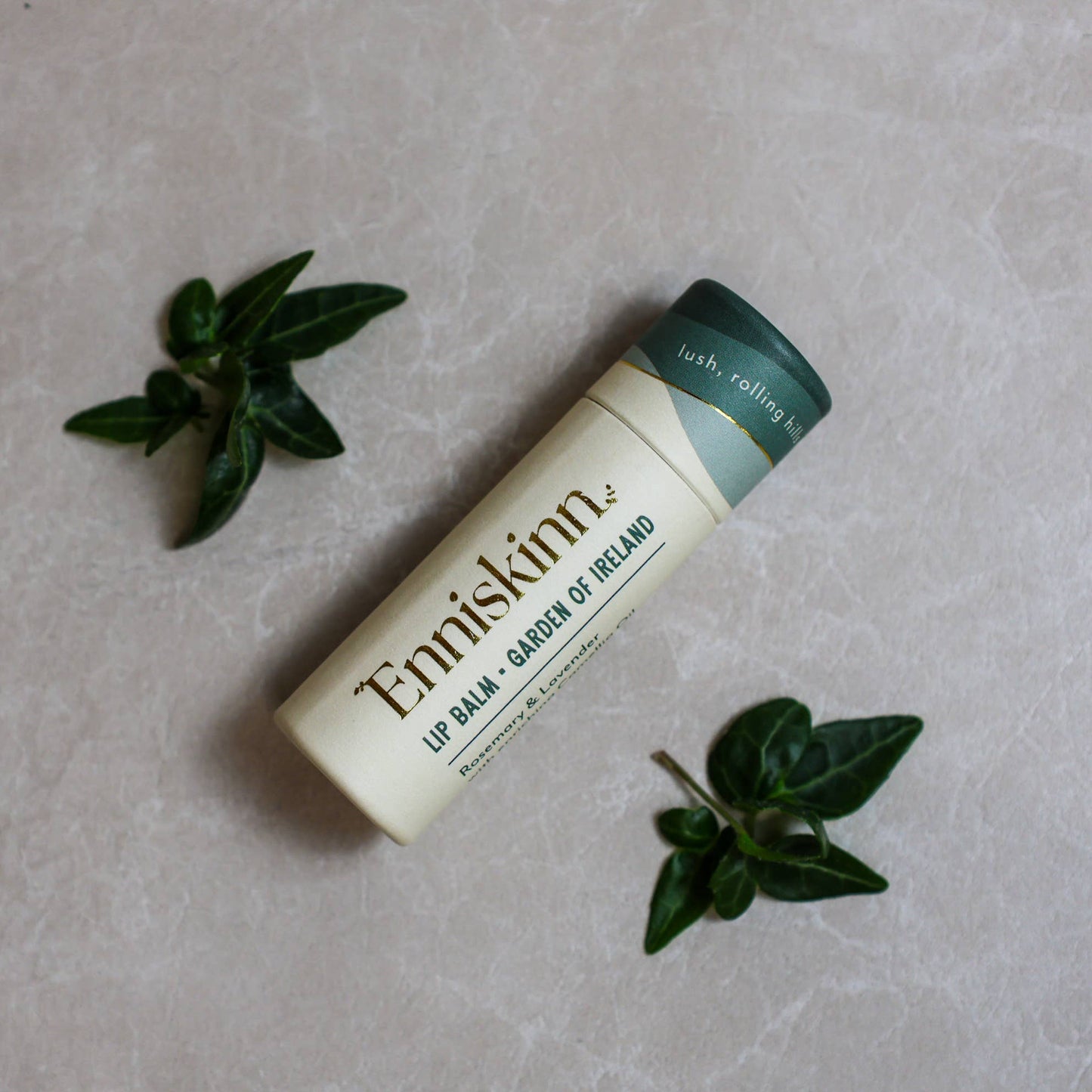Enniskinn lip balm on a textured surface with green leaves