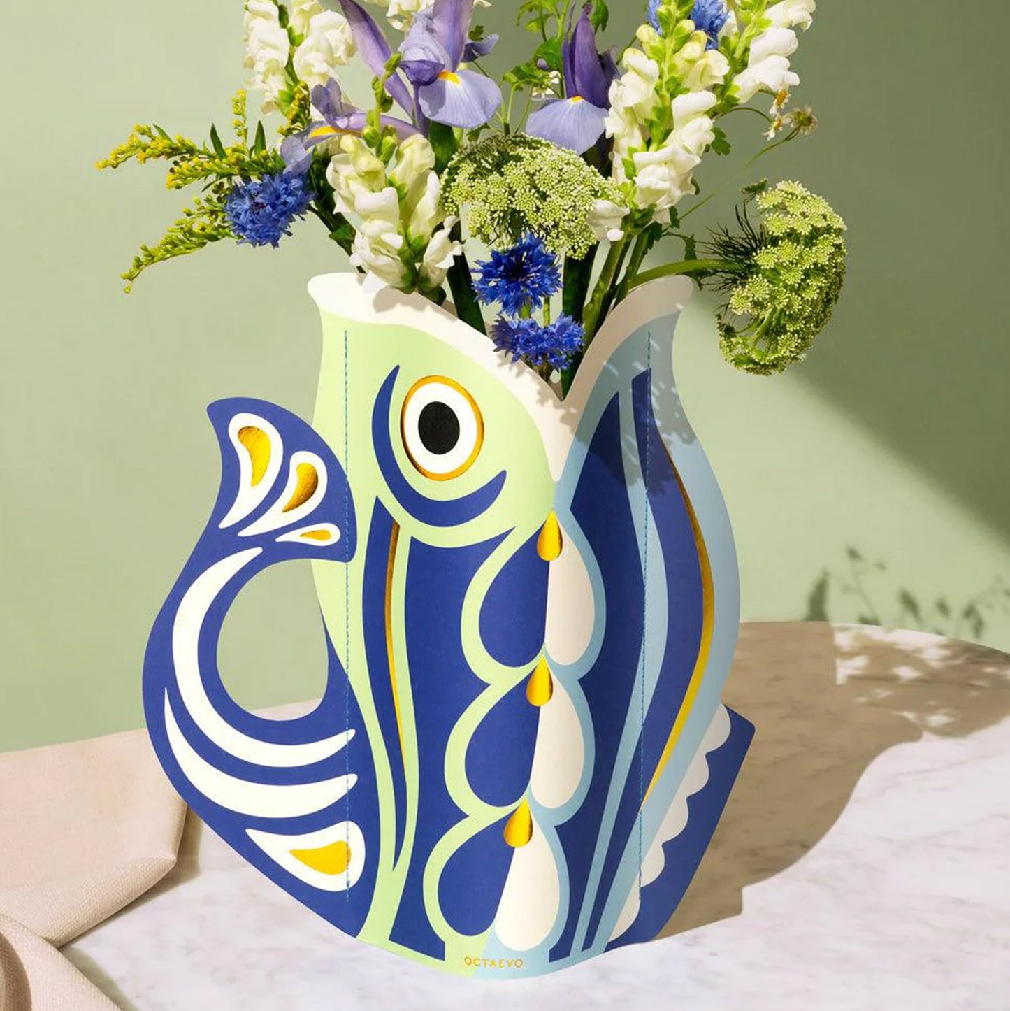 Colorful fish-shaped paper vase with flowers on a light green background
