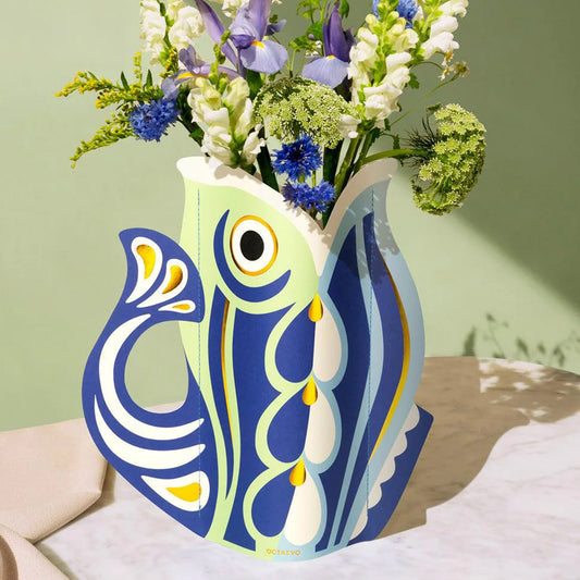 Colorful fish-shaped paper vase with flowers on a light green background