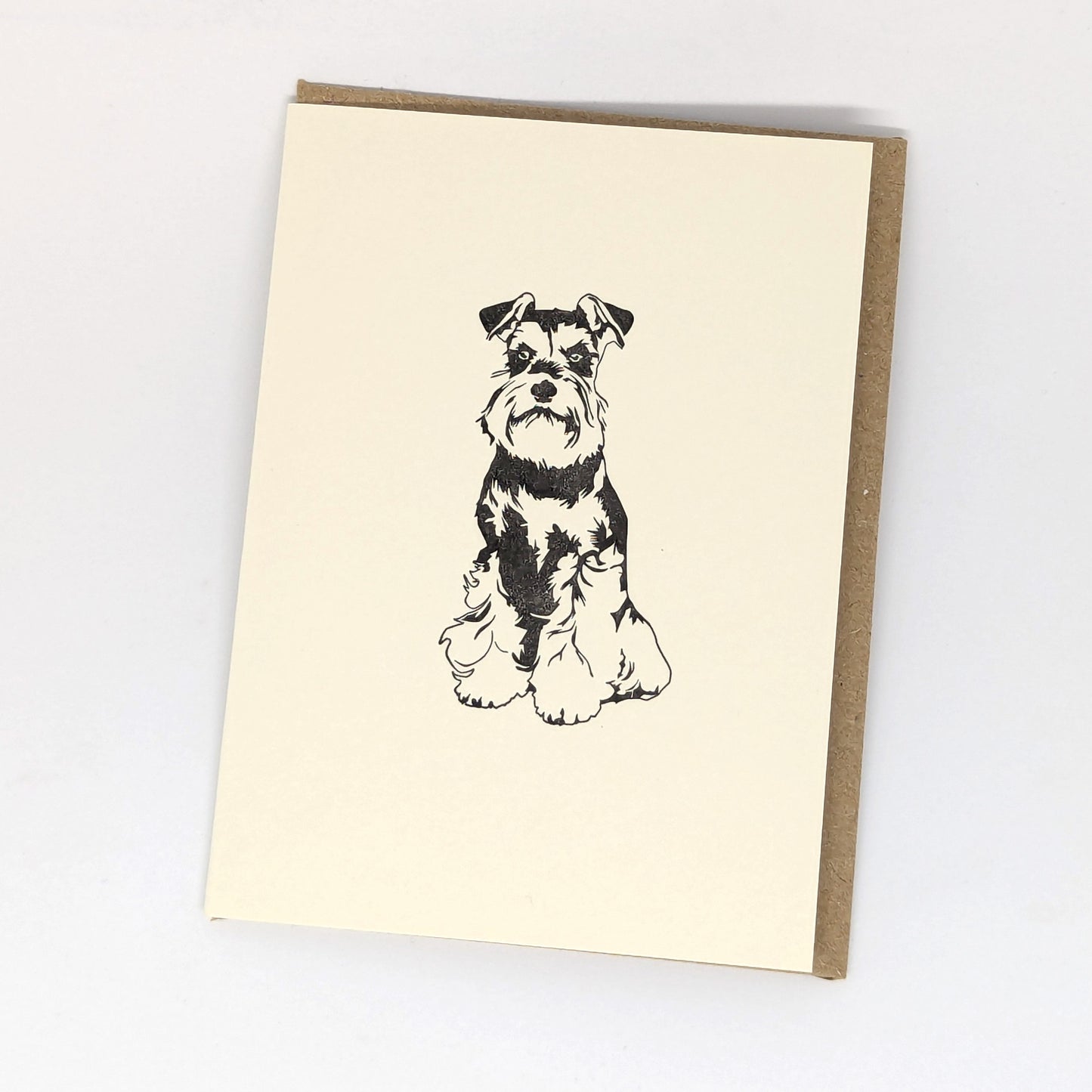 A letterpress greeting card featuring a black and white illustration of a Miniature Schnauzer dog,