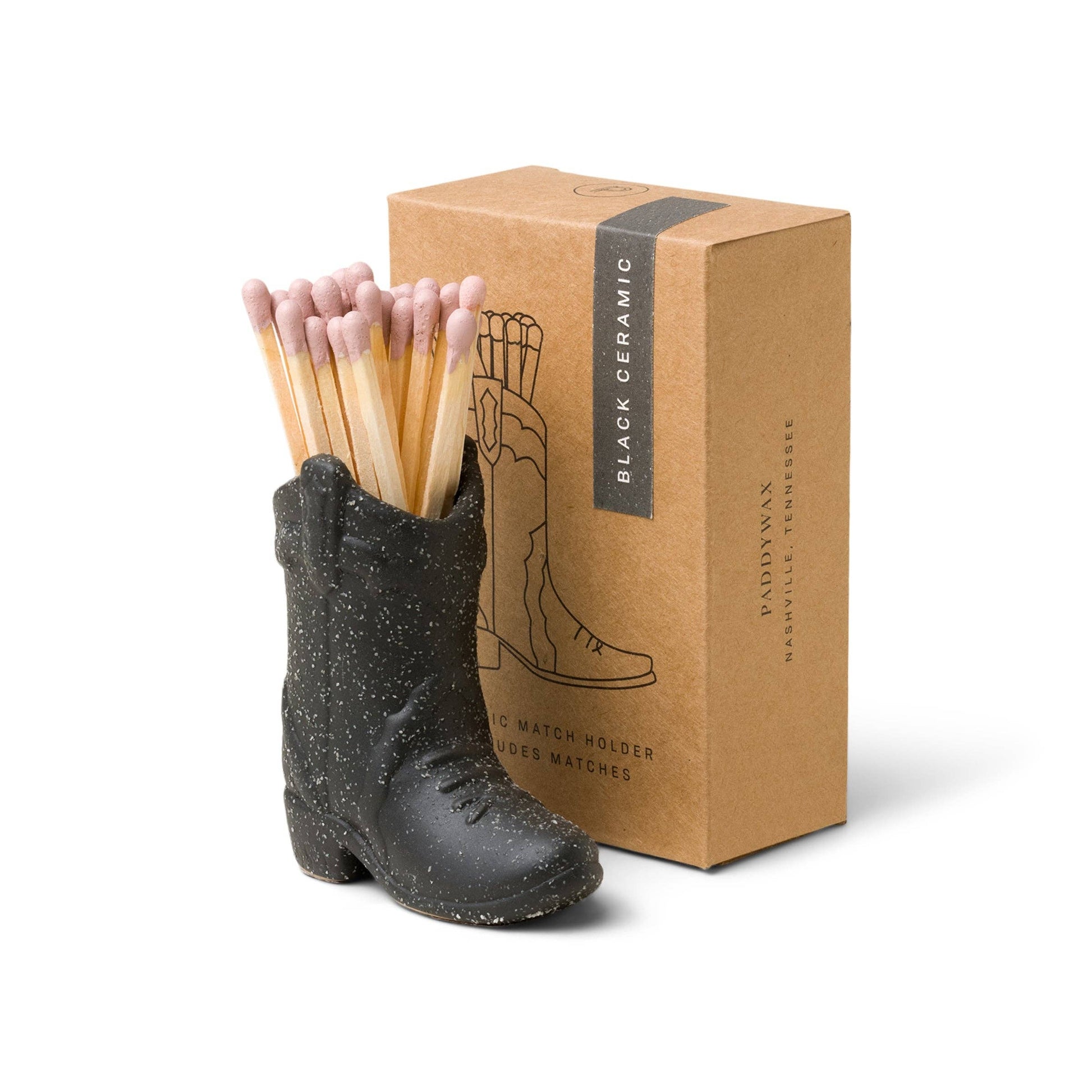 Black ceramic boot-shaped match holder with matches and a cardboard box on a white background