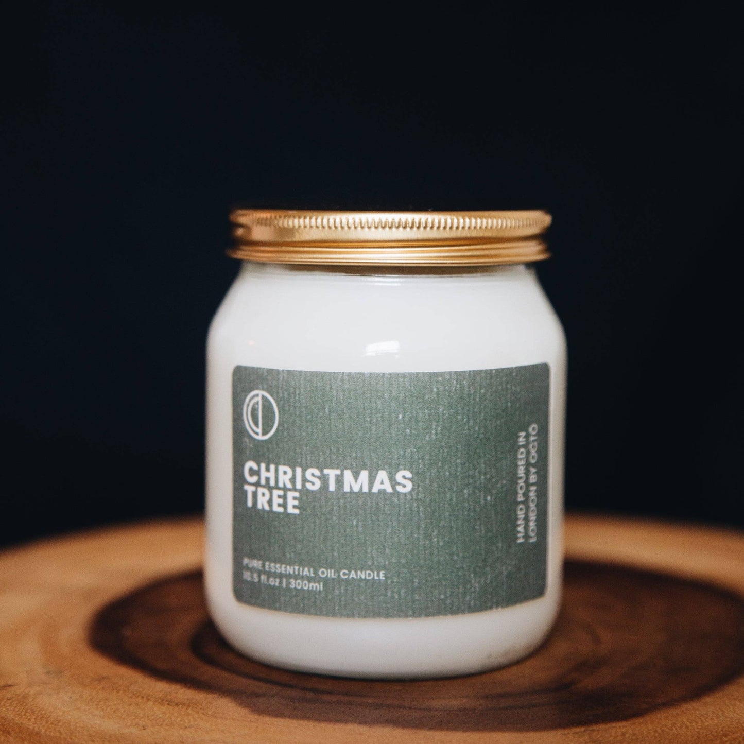Candle jar labeled 'Christmas Tree' on a wooden surface with a dark background