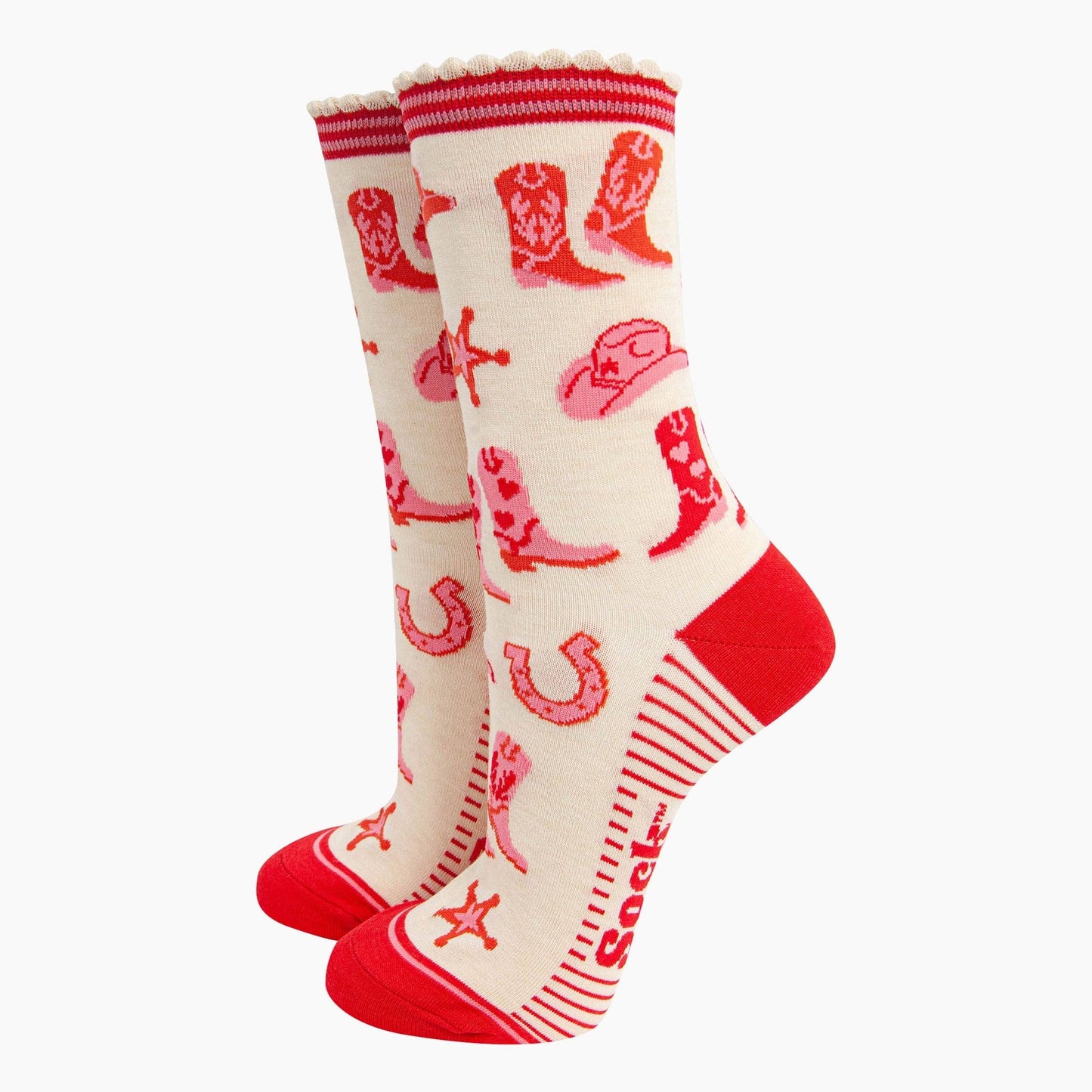 A pair of ankle socks with a western cowgirl theme, featuring red boots and accessories on a cream background with red stripes at the heel.