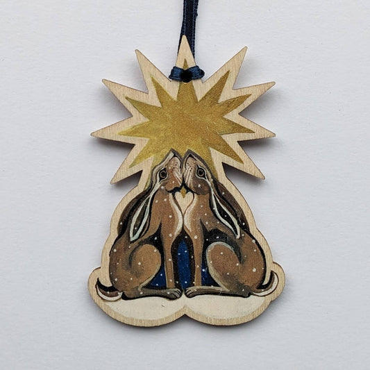 Decorative wooden ornament with two hares and a star on a light gray background
