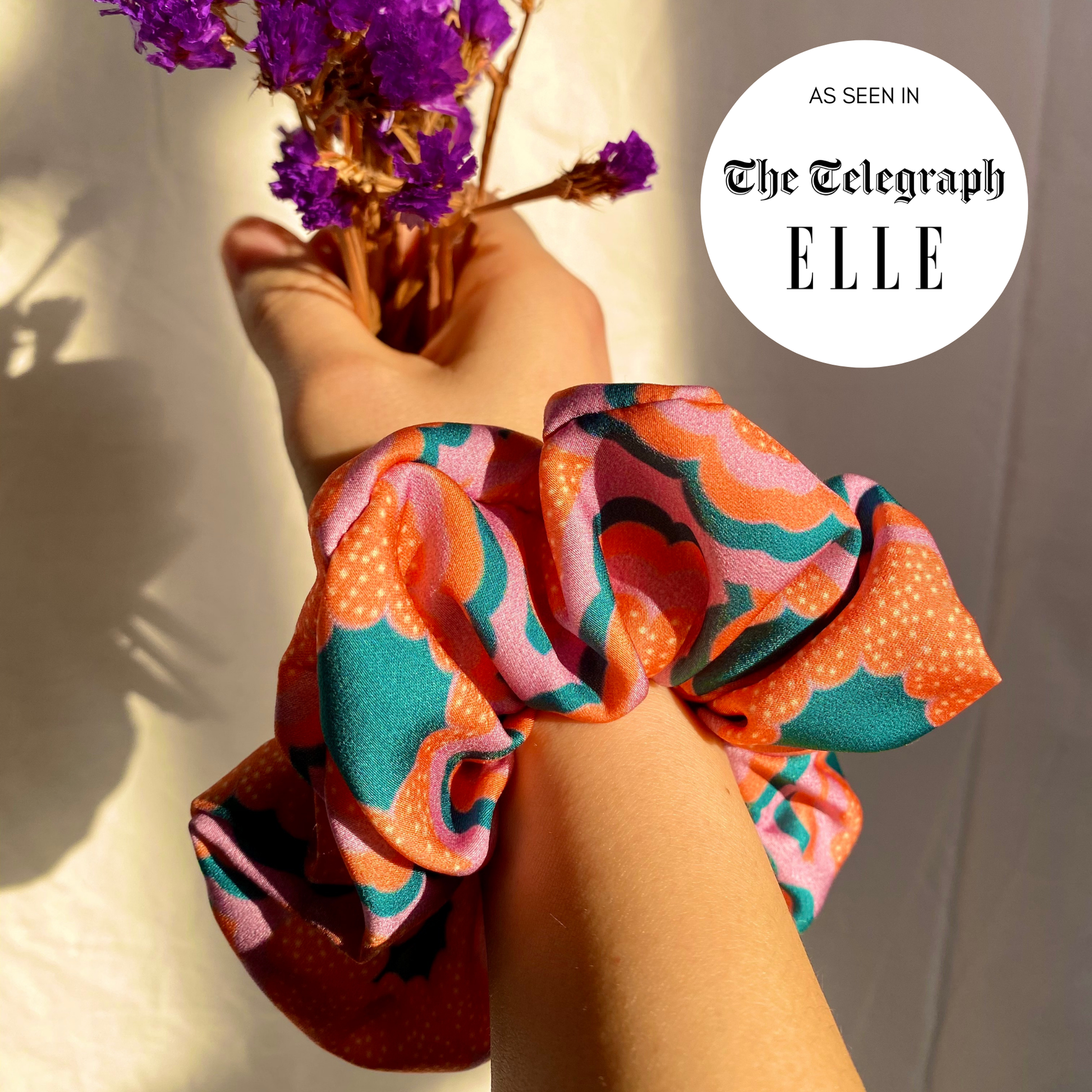 Colorful scrunchie held by a hand with purple flowers, featuring 'The Telegraph' and 'ELLE' logos.