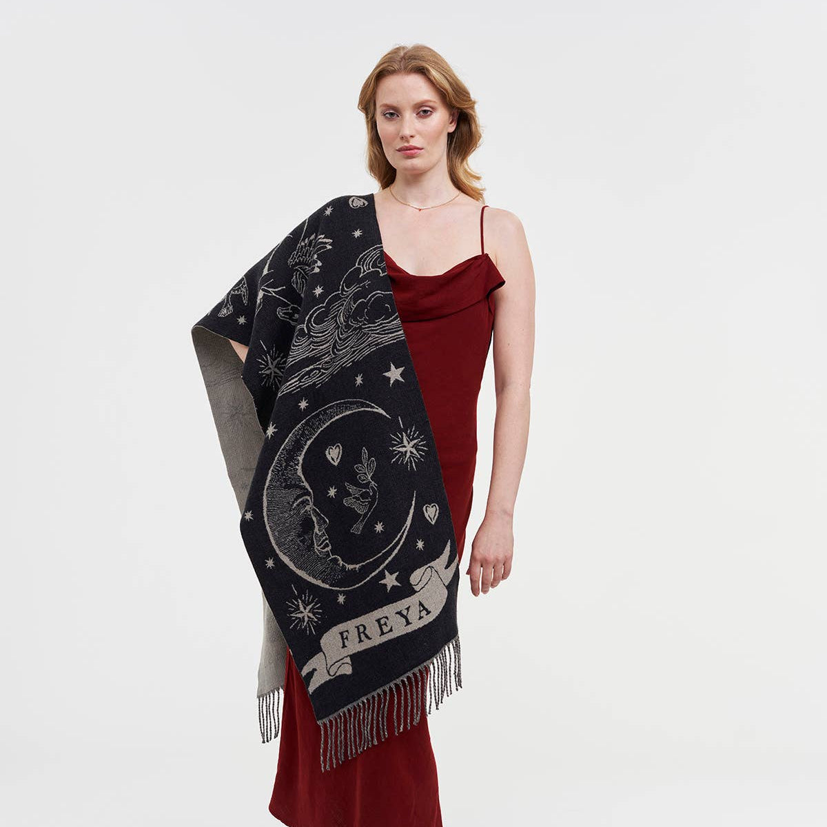 Woman in a red dress wearing a large black and white woven scarf with a crescent moon and a banner with the word Freya on it.