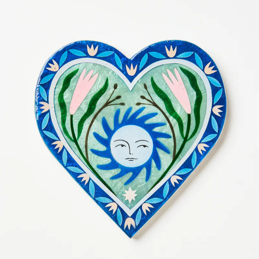 Heart-shaped decorative tile with a sun and plant design on a white background
