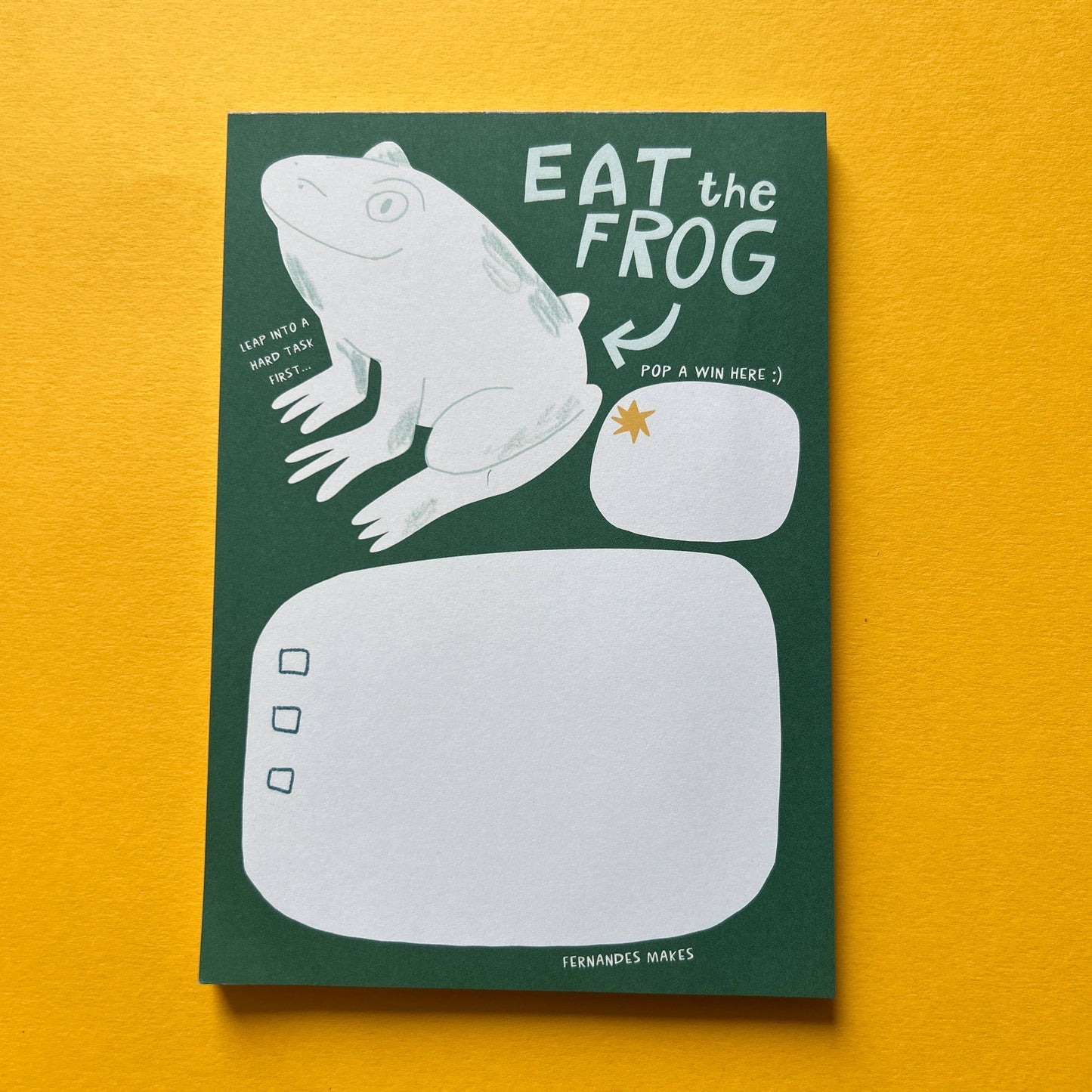Notepad with frog illustration and 'Eat the Frog' text on a yellow background
