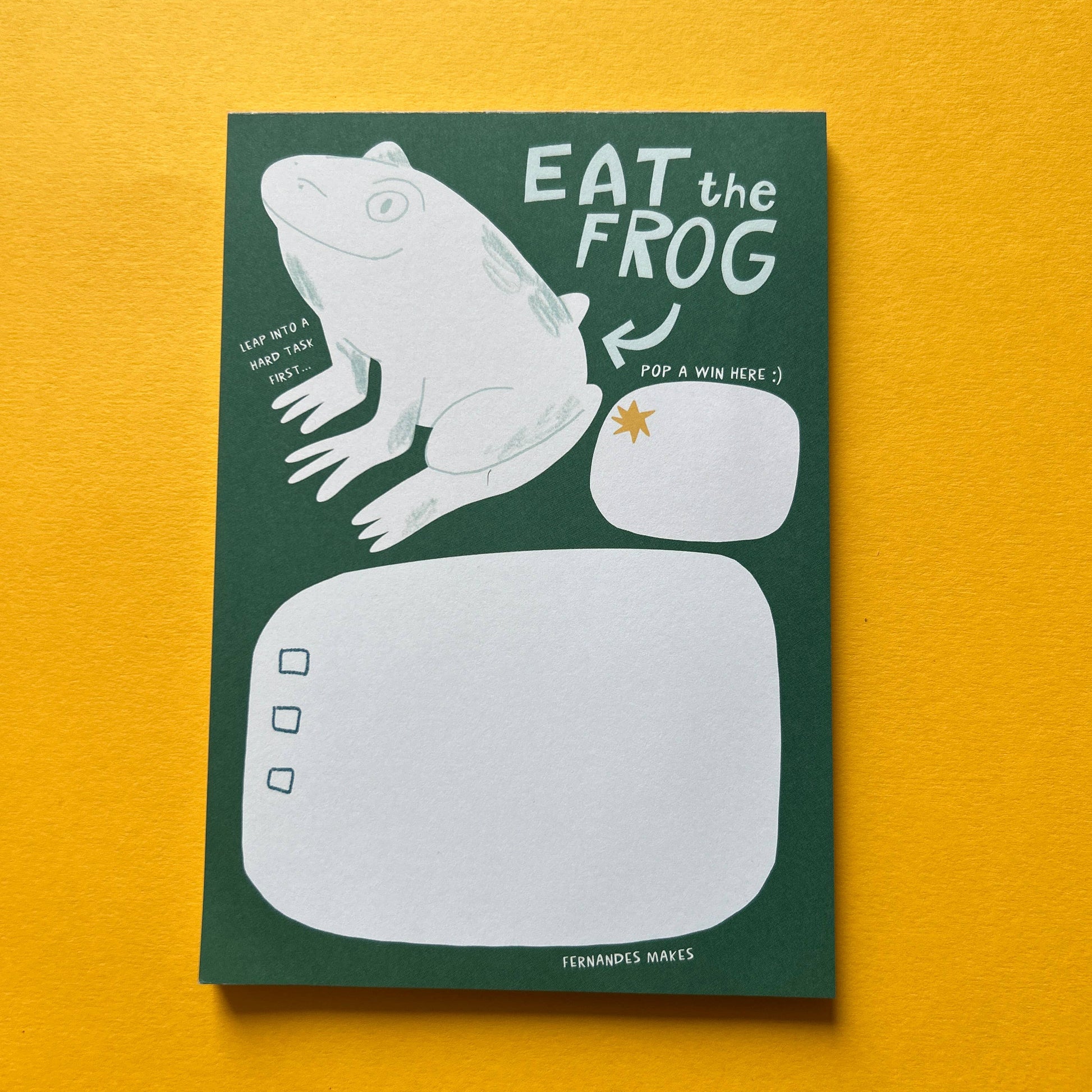 Notepad with frog illustration and 'Eat the Frog' text on a yellow background