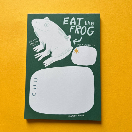 Notepad with frog illustration and 'Eat the Frog' text on a yellow background
