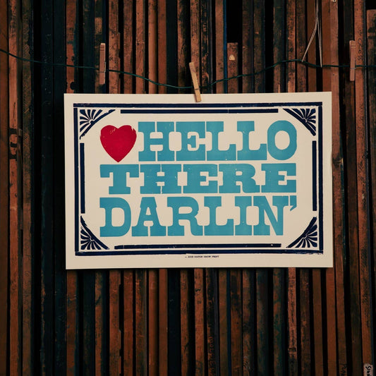 Sign with 'Hello There Darlin' text and heart symbol on a wooden background