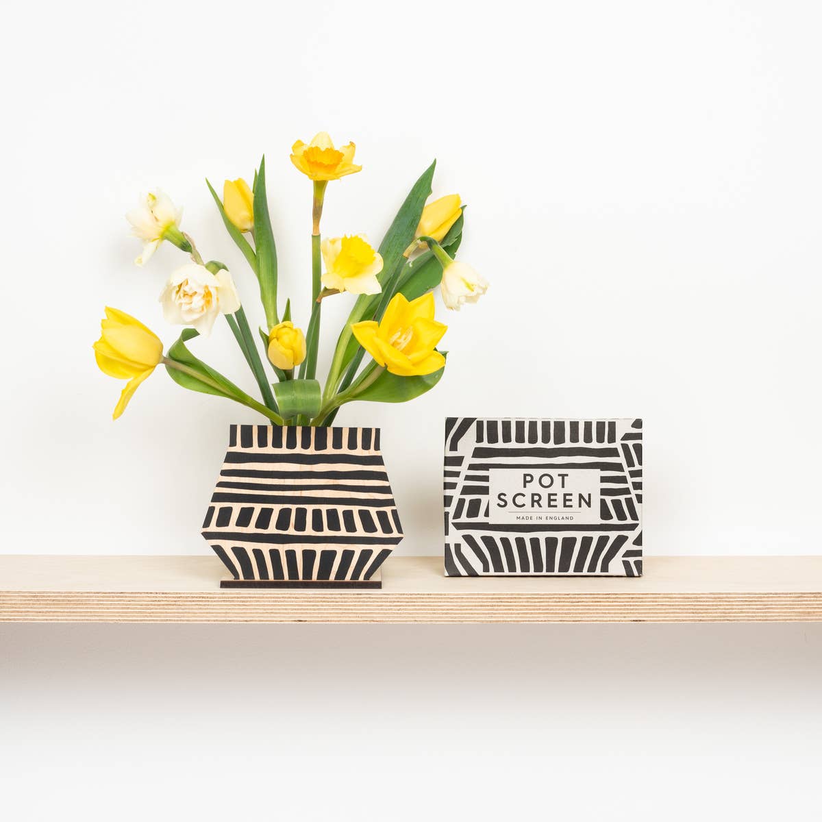 Black and white patterned pot screen with yellow flowers on a white background and the patterened packaging next to it