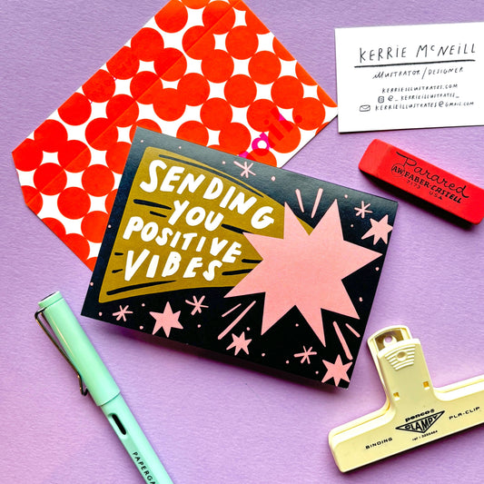 Greetings card with 'Sending You Positive Vibes' text on a purple background with stationery items.
