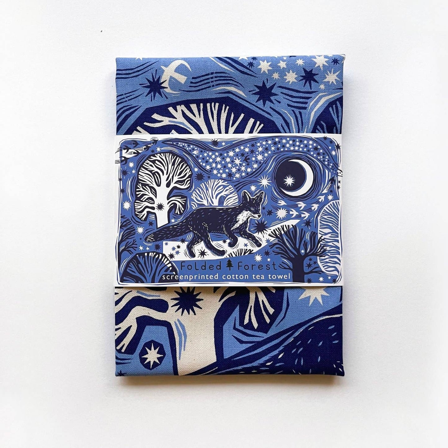 Folded tea towel with packaging showing a blue fox design