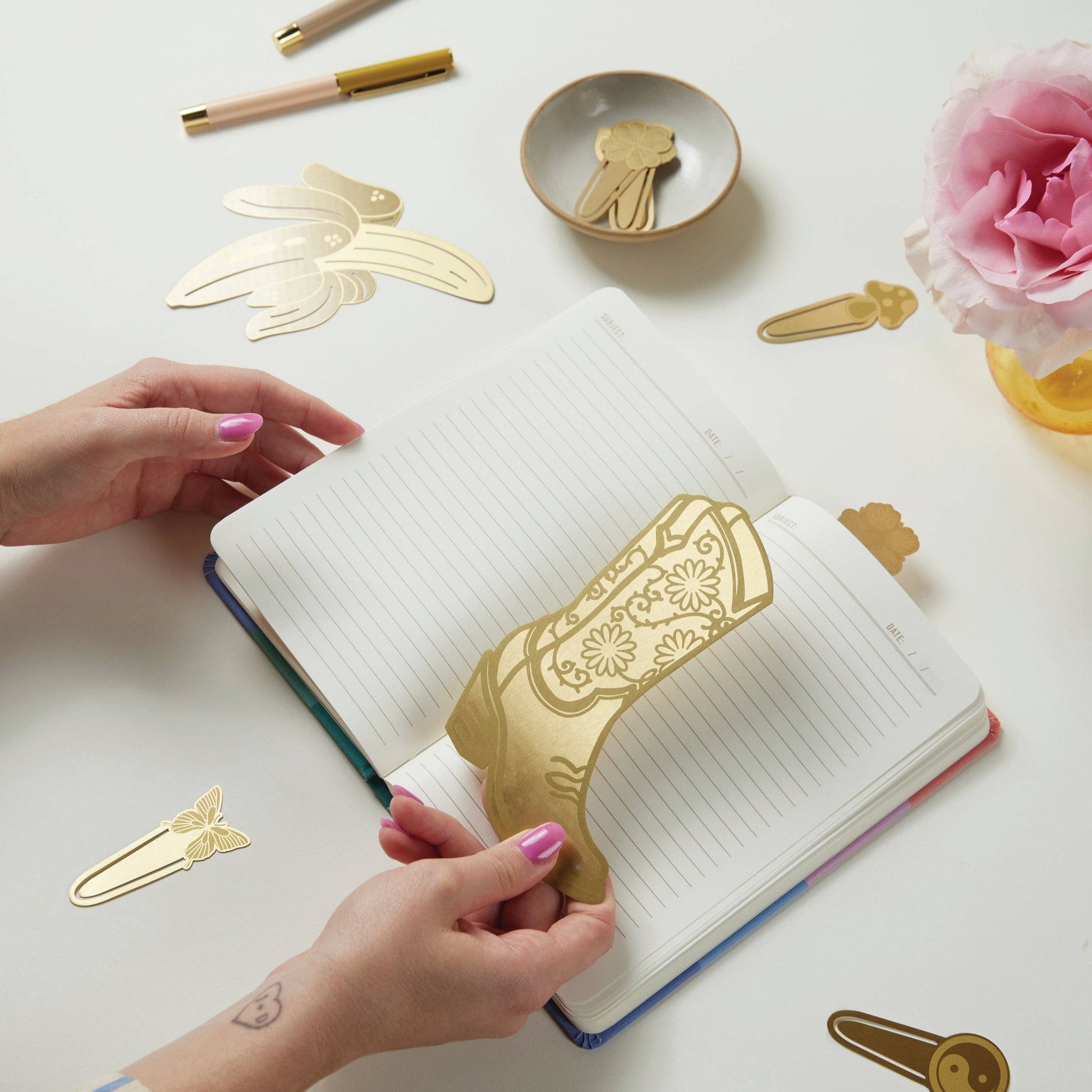 metal cowboy boot bookmark being held over an open diary
