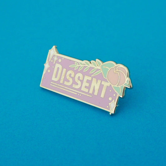 A pastel purple lapel pin with the word 'Dissent' written on it, with a floral design
