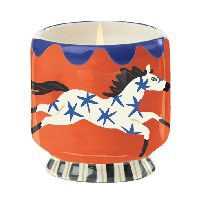Candle in a decorative holder with a horse design on an red and blue background