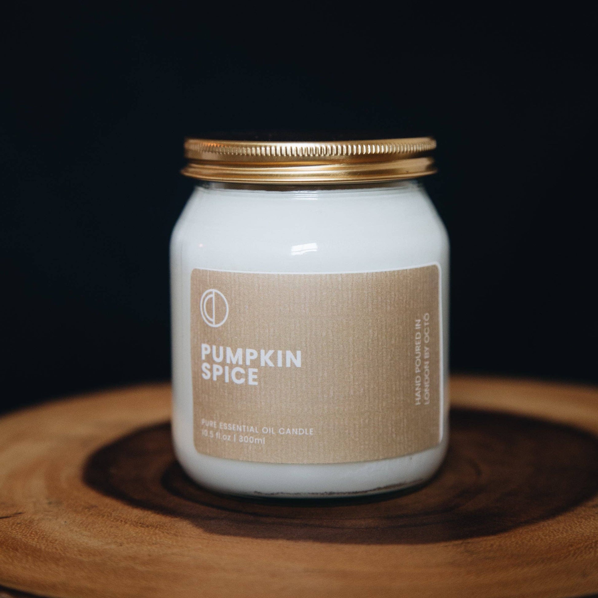 Pumpkin spice candle with a gold lid on a wooden surface