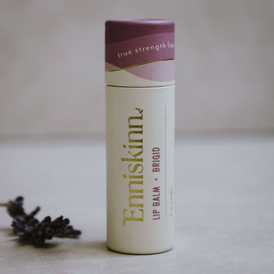 Lip balm container with purple cap and visible branding on a neutral background