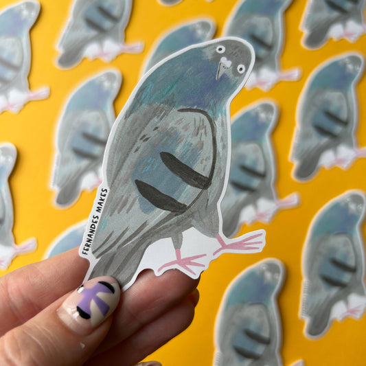 A hand holds a die-cut sticker of a pigeon against a bright yellow background filled with multiple copies of the same sticker.