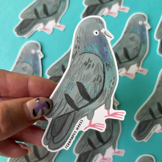 A hand holds a die-cut sticker shaped like a pigeon, with several matching pigeon stickers scattered on a bright turquoise background. 