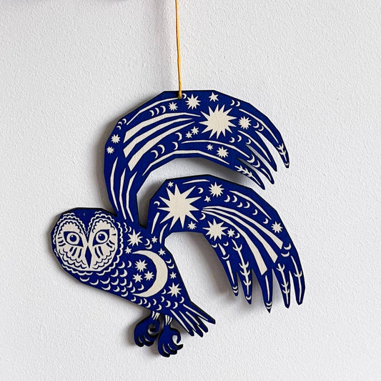 Decorative blue owl ornament with star and moon patterns on a white background