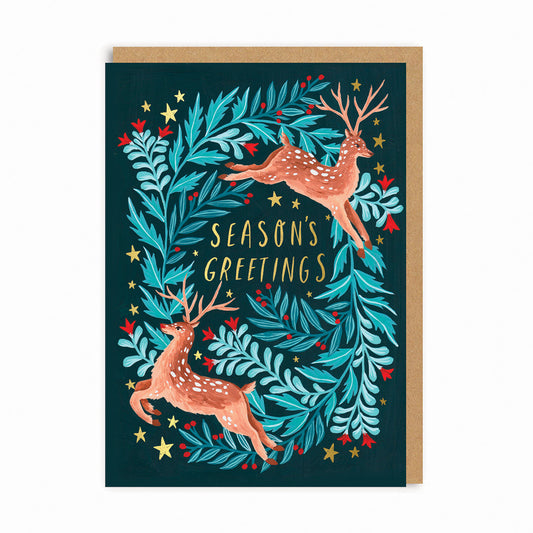 A beautiful greeting card with a painted illustration of two leaping deer and winter foliage with gold foiled stars and lettering that reads 'seasons greetings'