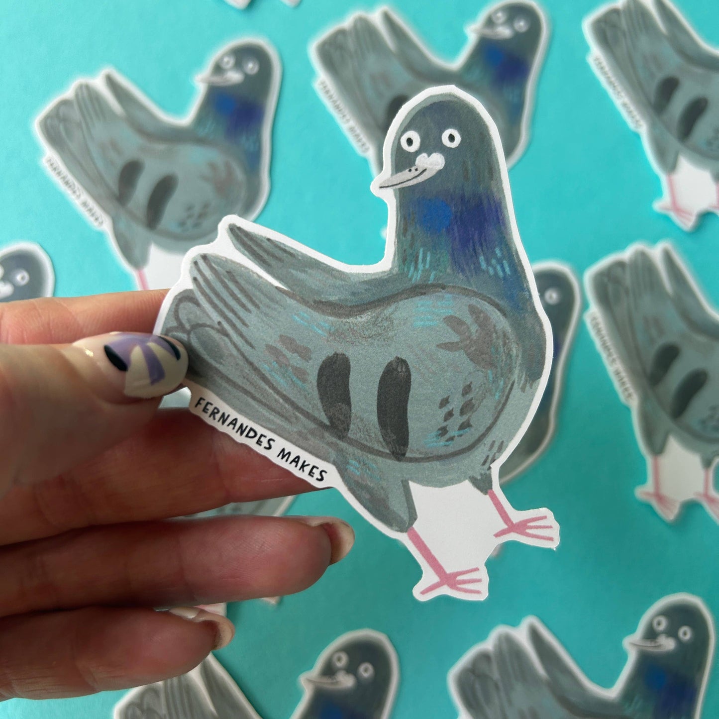 Hand holding a pigeon sticker with a turquoise background featuring more pigeon stickers.