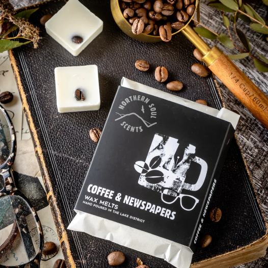 Wax melts packaging with coffee and newspapers design on a rustic background with coffee beans and a scoop.