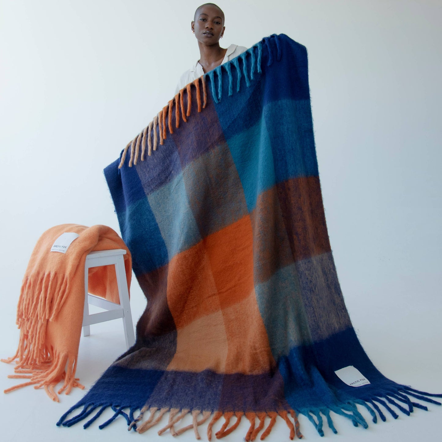 Colorful striped blanket with fringes on a white background