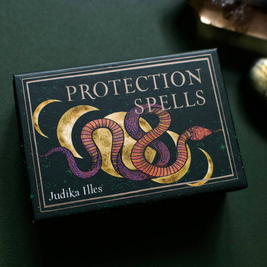 Box of 'Protection Spells' by Judika Illes on a dark green background with snake illustration on the packaging.