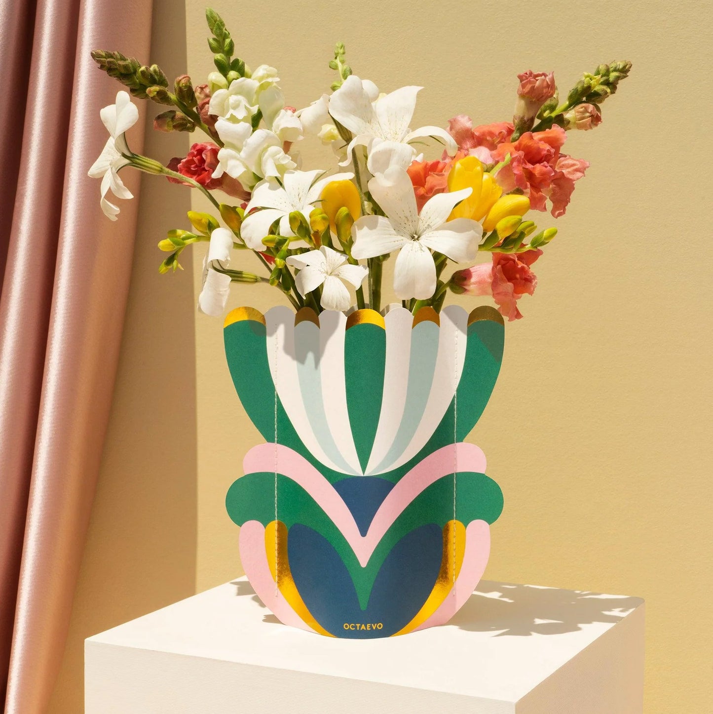 Colorful paper vase with flowers against a beige wall