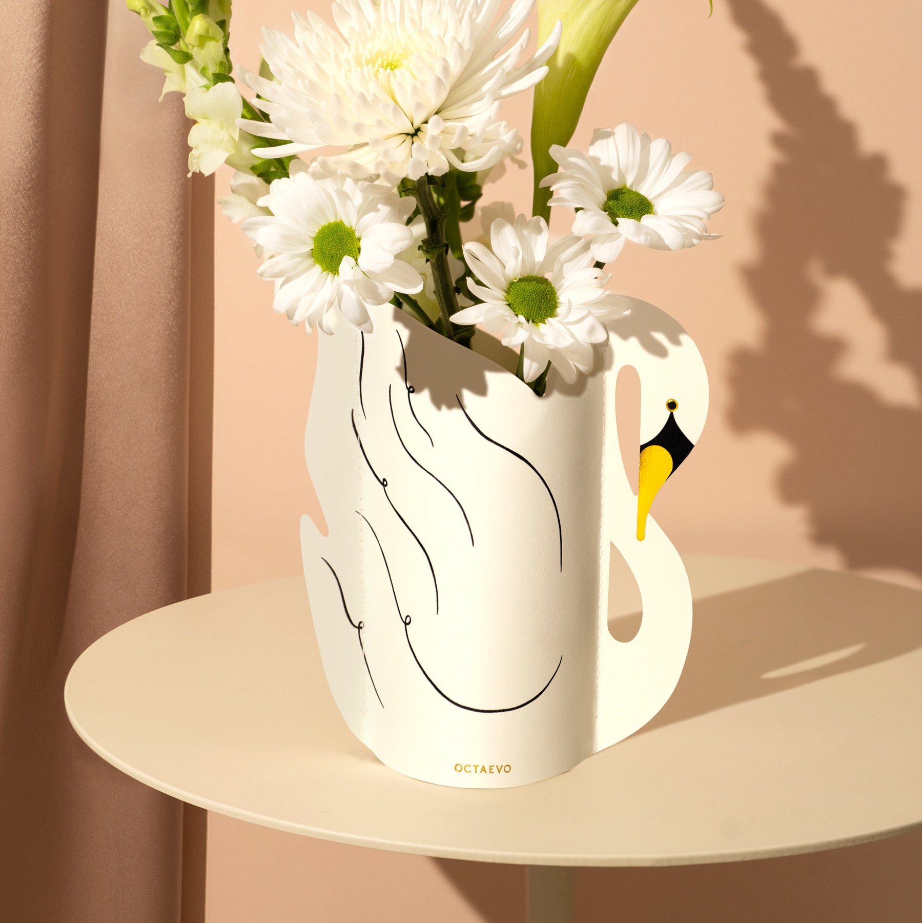 Swan-shaped vase with flowers on a beige surface against a pink background